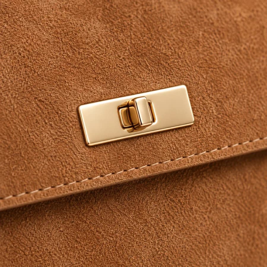Tan suede surface, stitching and gold-tone handbag hardware detail