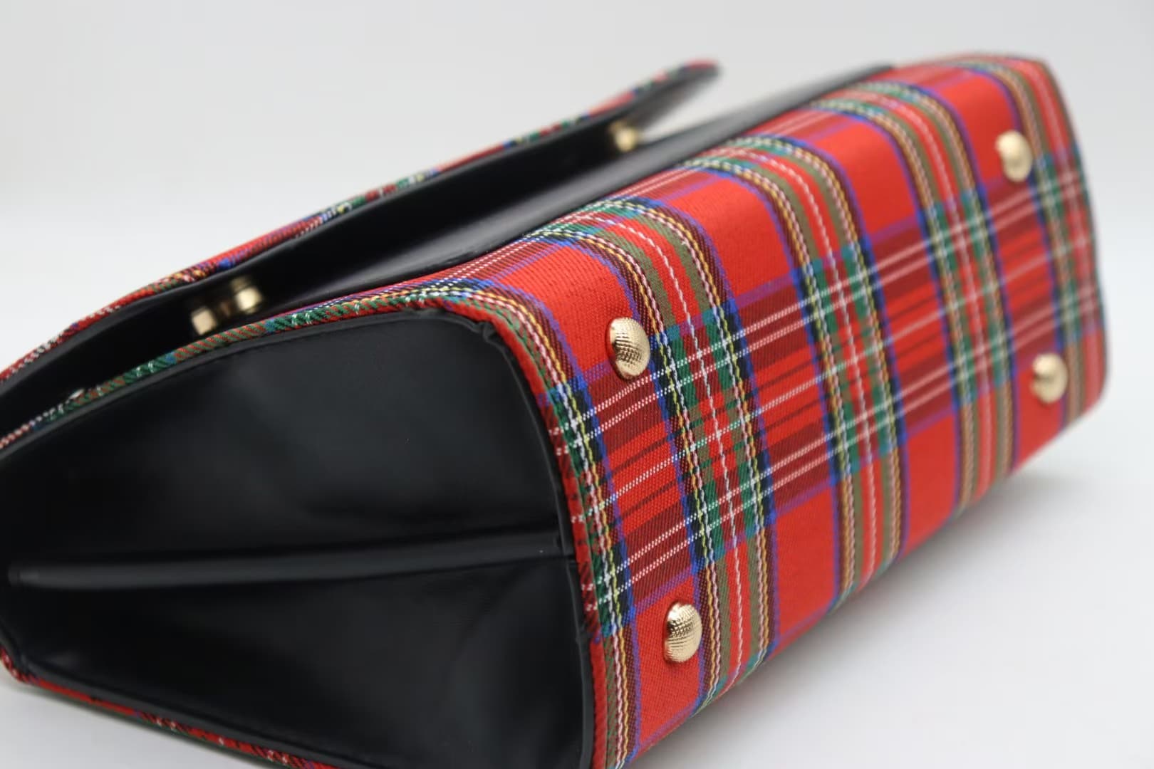 Close view of red tartan bag base with black side panel and metal feet