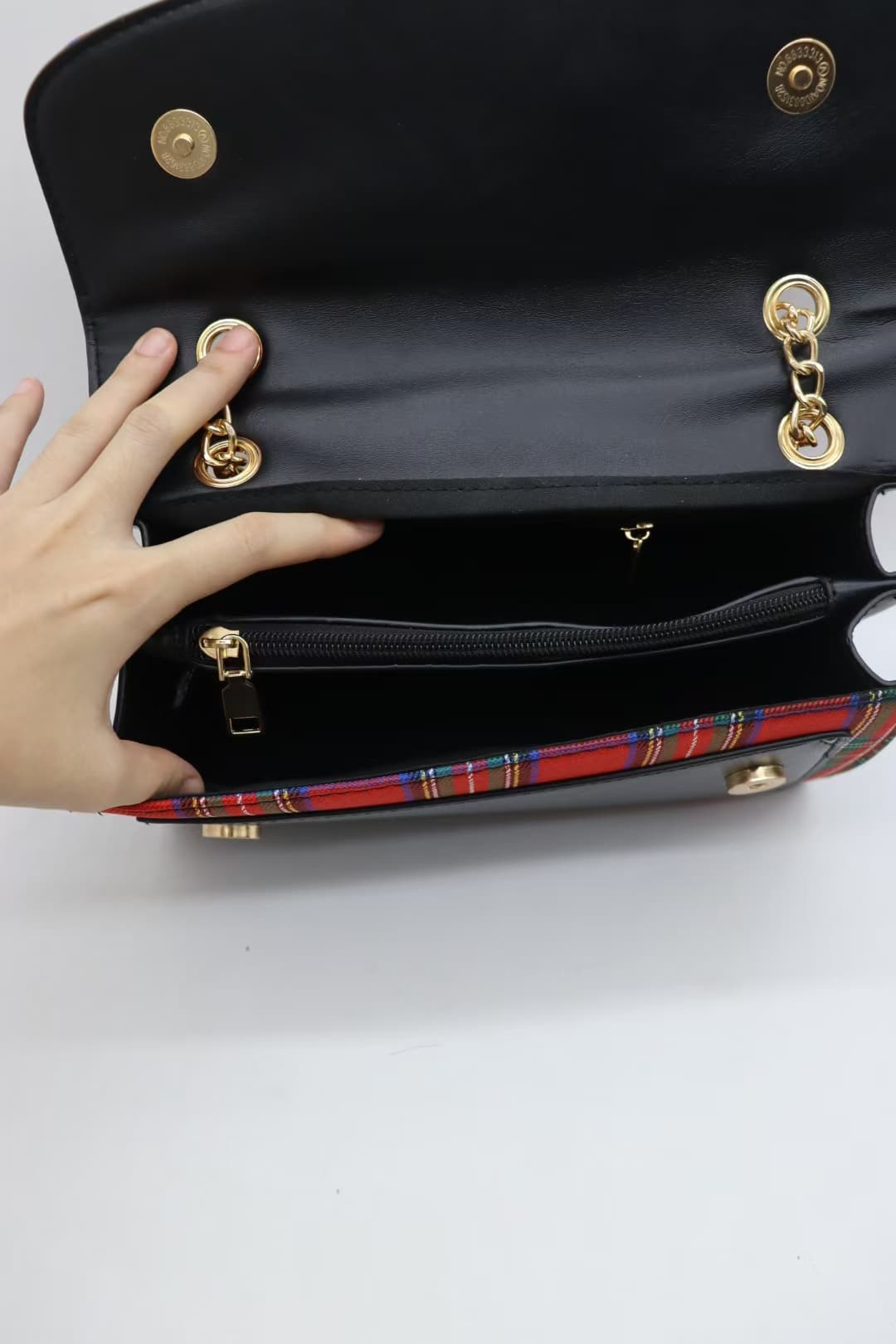 Interior of red tartan crossbody bag with zipped pocket and open compartment