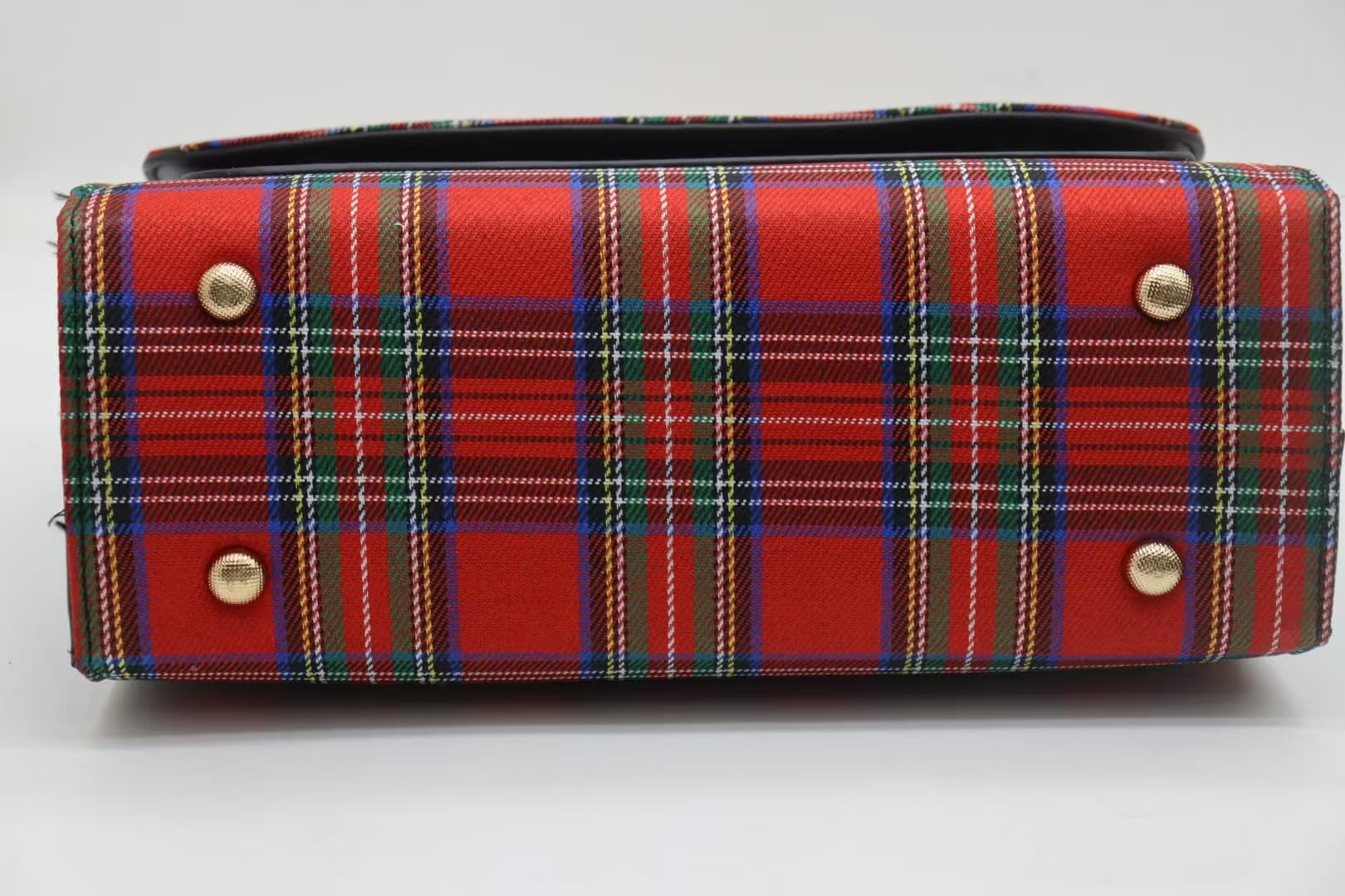 Base of red tartan crossbody bag with four protective metal feet